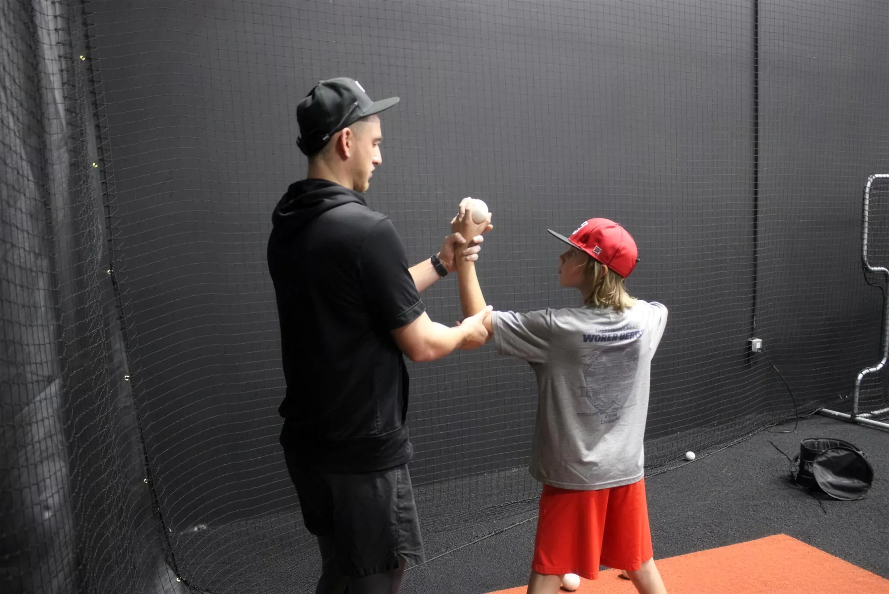 Evolve coach adjusting a young player's grip during a hitting lesson