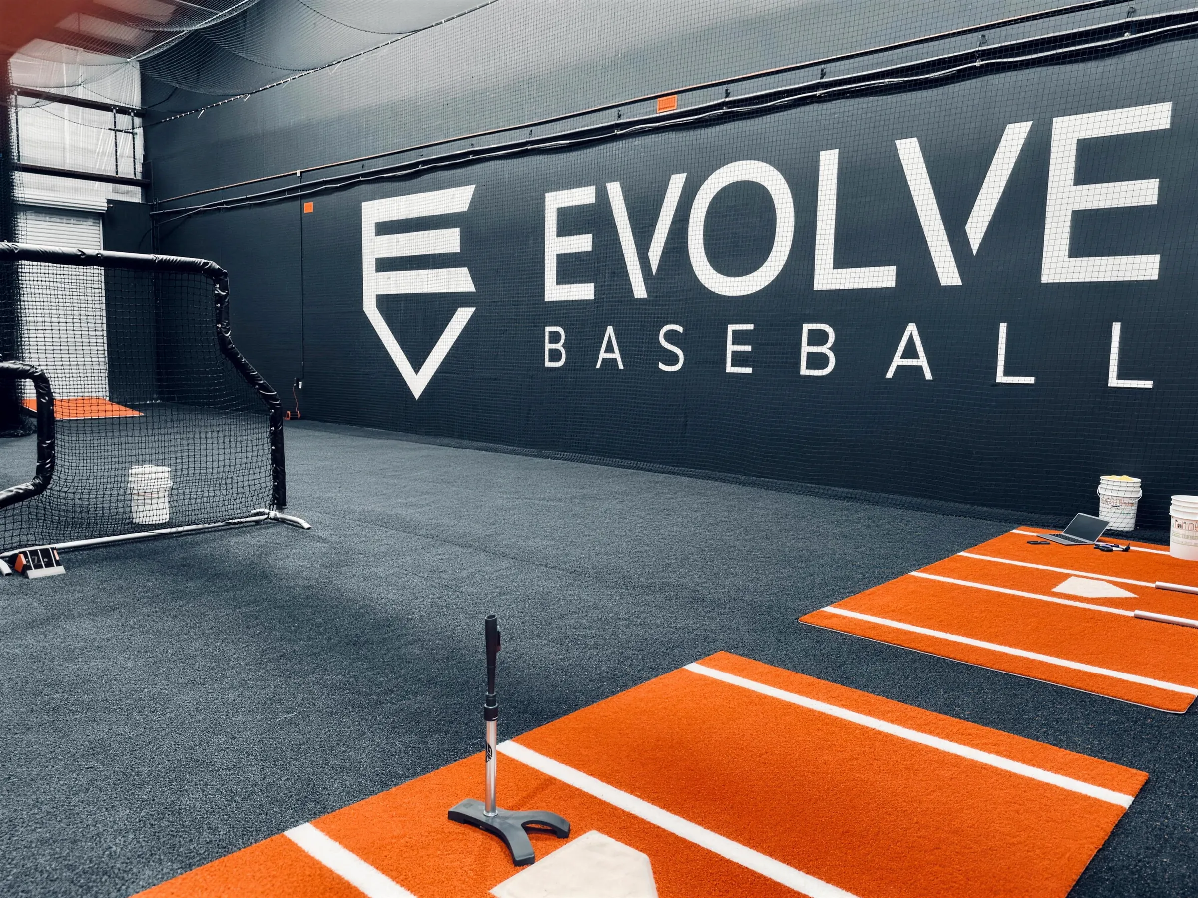 Evolve Baseball training facility with orange turf lanes and the Evolve wall logo